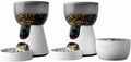 Two automatic camera cat feeders and a water fountain set up side by side