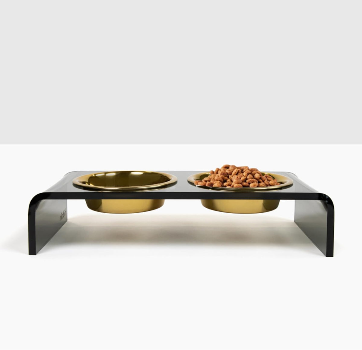 Smoke grey acrylic raised stand holding two gold dog bowls