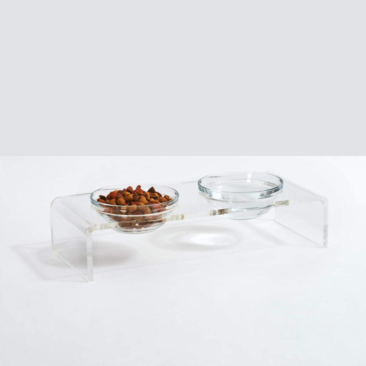 Clear acrylic raised stand holding two round glass dog bowls