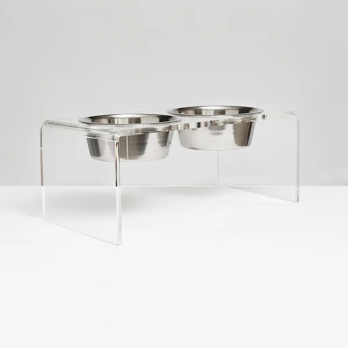 Clear acrylic elevated stand holding two silver stainless steel dog bowls