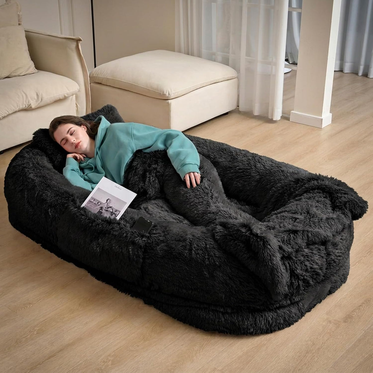 Black giant faux fur human dog bed with blanket on a floor