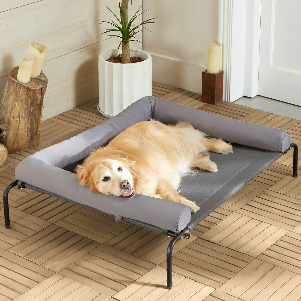 Grey raised mesh dog cot with sloped headrest outdoors