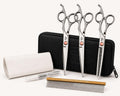 Three stainless steel dog grooming shears laid beside a zipper storage case