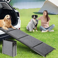 Long folding dog ramp with gray non-slip rug surface leaning on an SUV