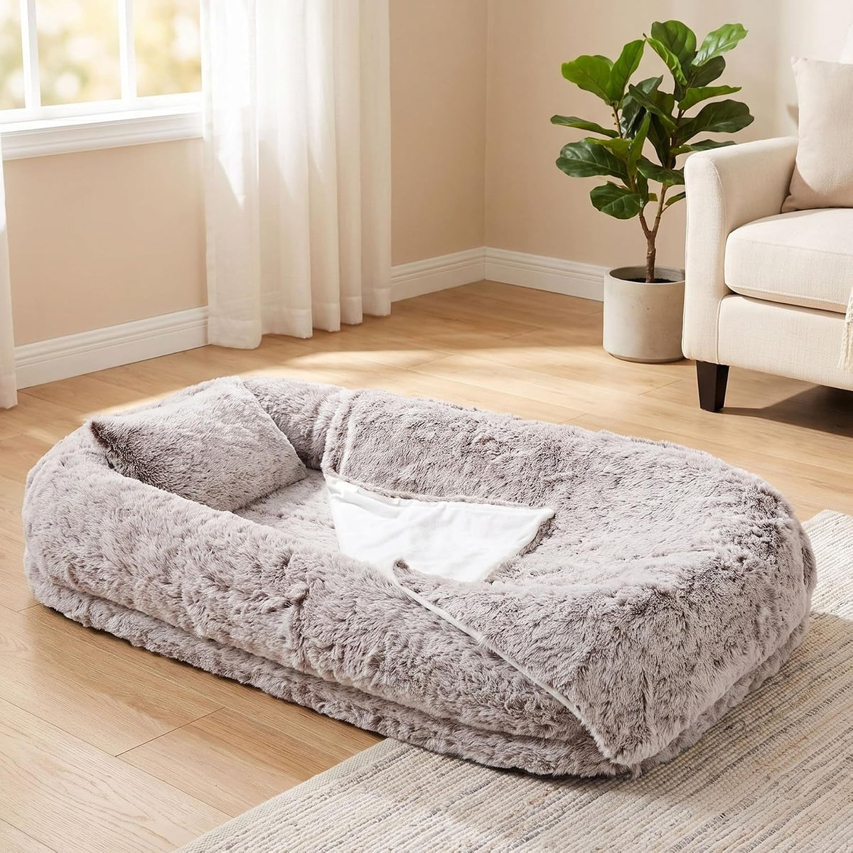 Large dark brown human-size dog bed with pillow and blanket