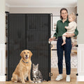 Black 65 inch tall retractable mesh pet gate in a doorway