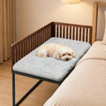 Metal frame bedside dog bed with removable cushion next to a mattress