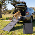 Folding aluminum dog ramp with gray rug surface leaning on an SUV